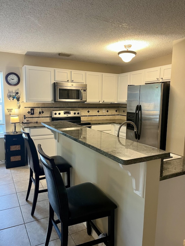 kitchen featuring a kitchen bar, white cabinets, and appliances with stainless steel finishes