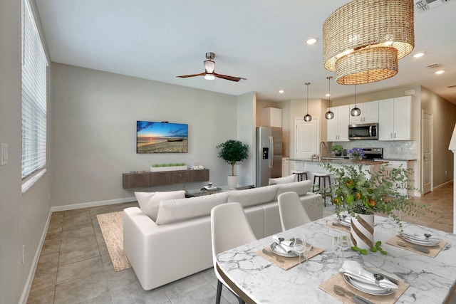 tiled dining space with sink and ceiling fan with notable chandelier