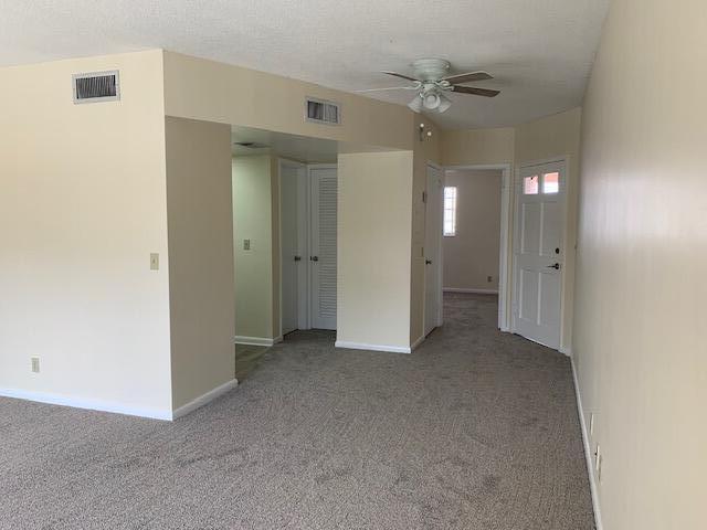 empty room featuring ceiling fan and light carpet