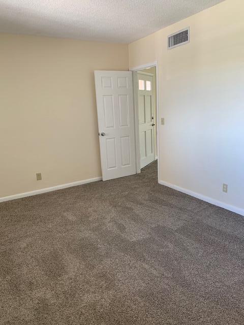 spare room with a textured ceiling and dark colored carpet