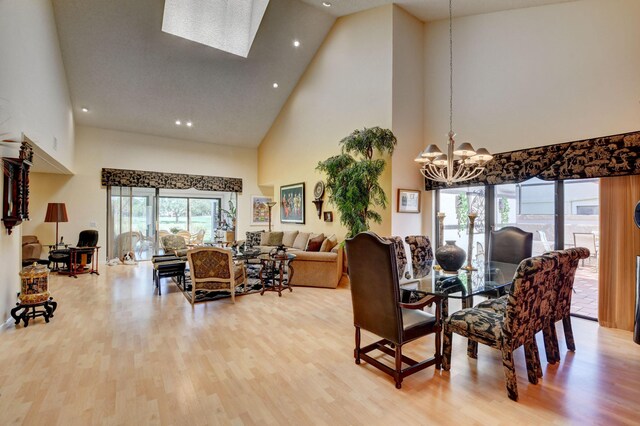 dining room with a chandelier, high vaulted ceiling, a skylight, and light hardwood / wood-style floors