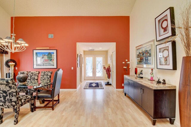 entryway featuring light wood-type flooring, a chandelier, a textured ceiling, and french doors