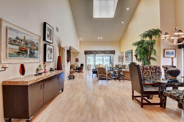 dining space with a chandelier, high vaulted ceiling, light hardwood / wood-style flooring, and a skylight