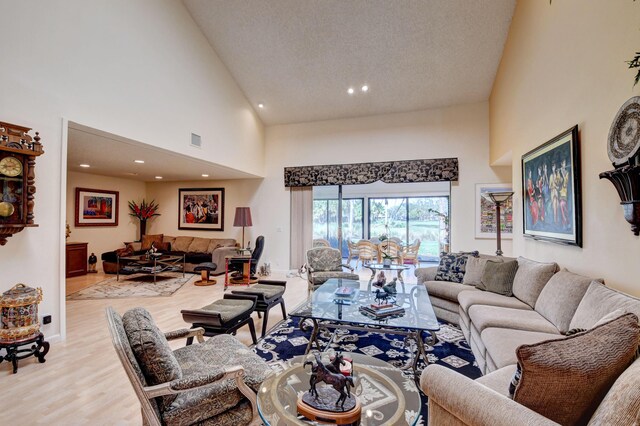 living room with a textured ceiling, light hardwood / wood-style flooring, and high vaulted ceiling