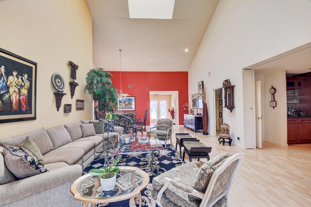 living room with high vaulted ceiling, light hardwood / wood-style flooring, and a skylight