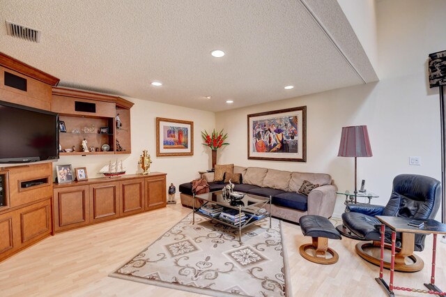 living room with a textured ceiling and light wood-type flooring