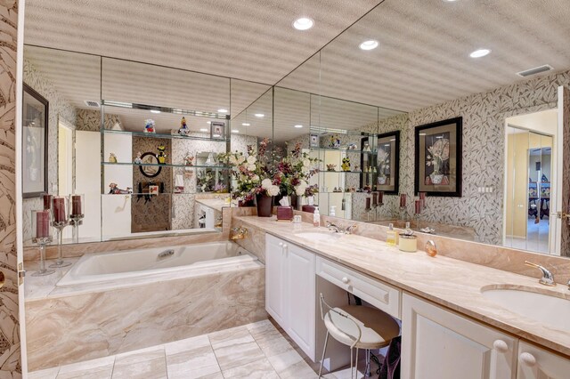 bathroom with a textured ceiling, tiled bath, and vanity