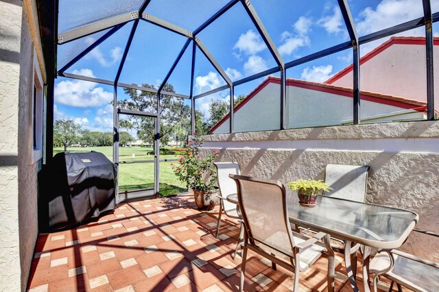 view of patio with glass enclosure and a grill