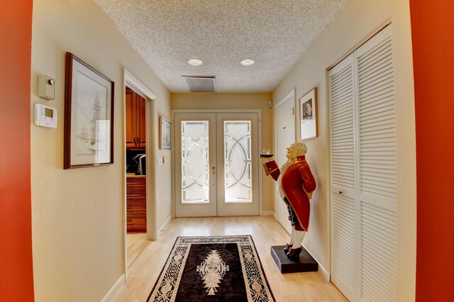 interior space with french doors, a textured ceiling, and light hardwood / wood-style flooring