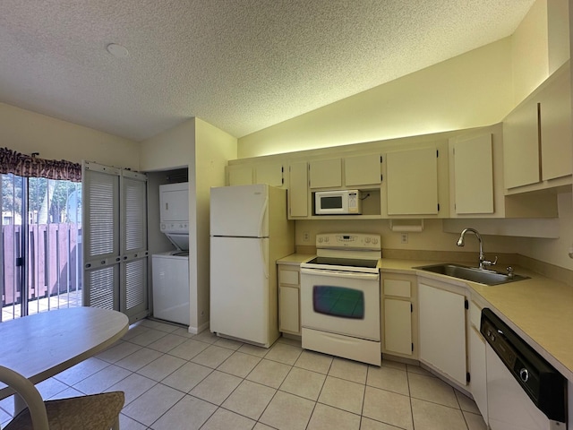 kitchen with a sink, white appliances, a textured ceiling, stacked washer / drying machine, and vaulted ceiling