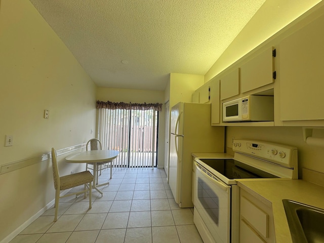 kitchen featuring a textured ceiling, light tile patterned floors, white appliances, a sink, and light countertops