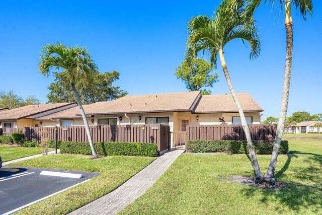 single story home featuring a front lawn, a fenced front yard, stucco siding, and uncovered parking