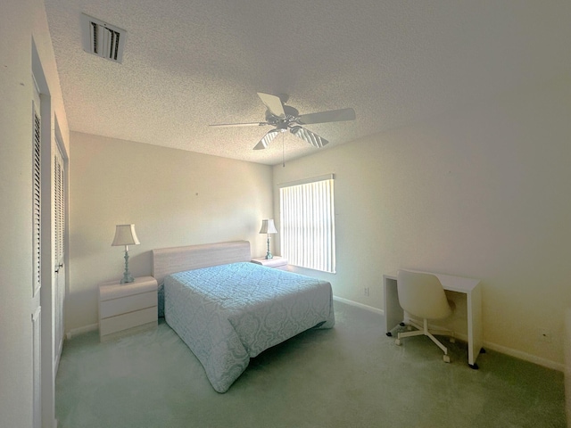 bedroom with a textured ceiling, visible vents, baseboards, and carpet floors
