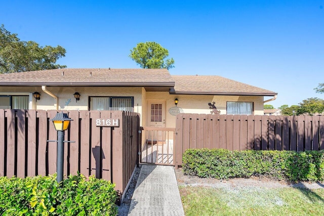 view of front of house featuring stucco siding, fence, and a gate