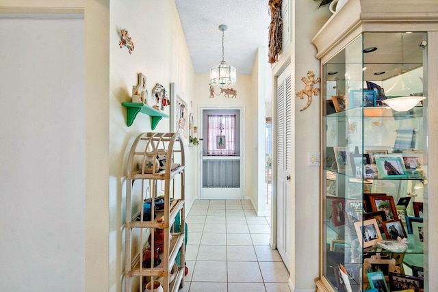 interior space featuring a textured ceiling, light tile patterned floors, and a chandelier