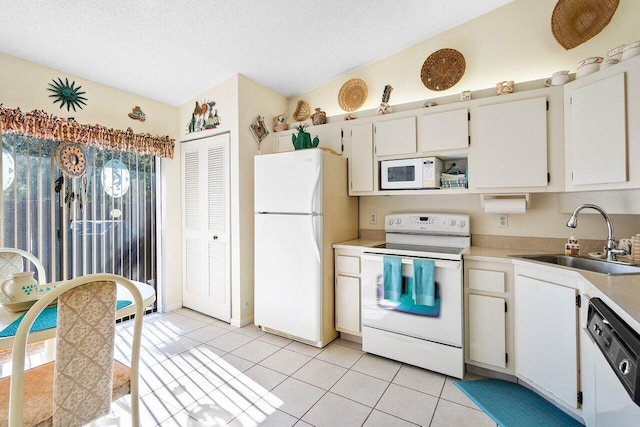 kitchen featuring white appliances, light tile patterned flooring, sink, and white cabinets