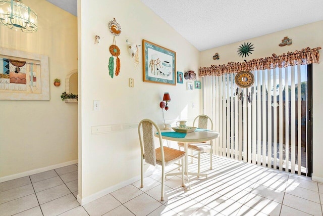 tiled dining area featuring a textured ceiling, vaulted ceiling, and a chandelier