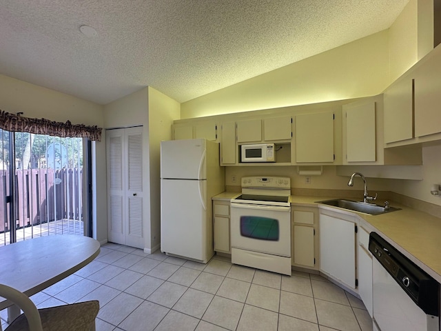 kitchen featuring light tile patterned floors, a sink, a textured ceiling, white appliances, and lofted ceiling