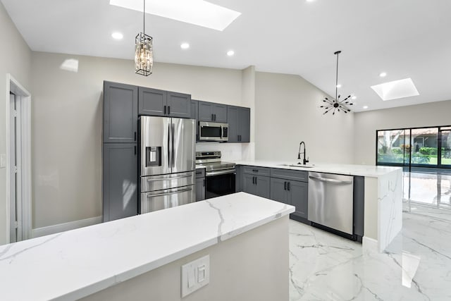 kitchen with lofted ceiling with skylight, pendant lighting, stainless steel appliances, and light stone counters