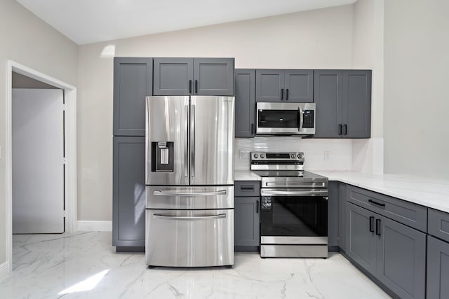 kitchen with appliances with stainless steel finishes, gray cabinetry, lofted ceiling, and backsplash