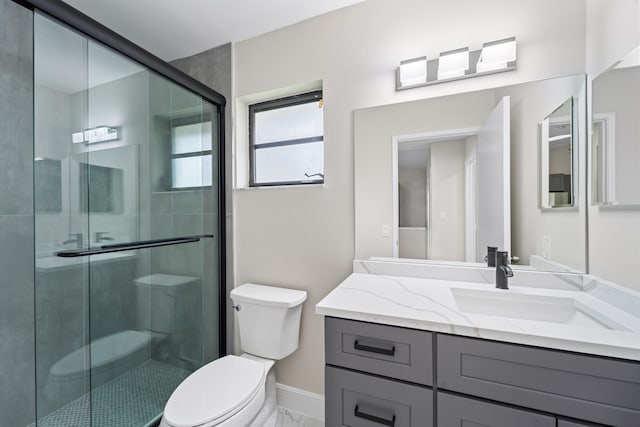 bathroom with vanity, toilet, and a shower with door