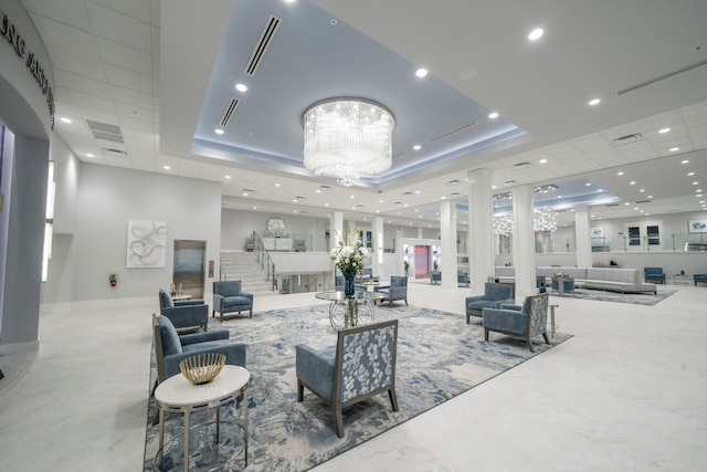 interior space with a raised ceiling, an inviting chandelier, and ornate columns