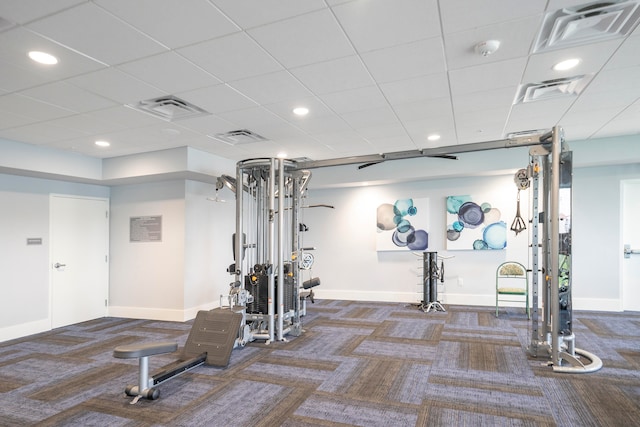 workout area with a paneled ceiling and dark colored carpet