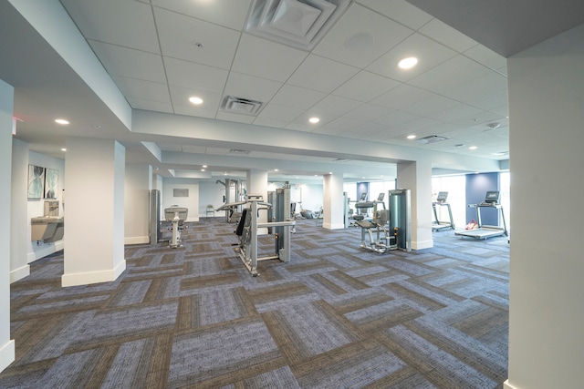 gym featuring a paneled ceiling and dark carpet