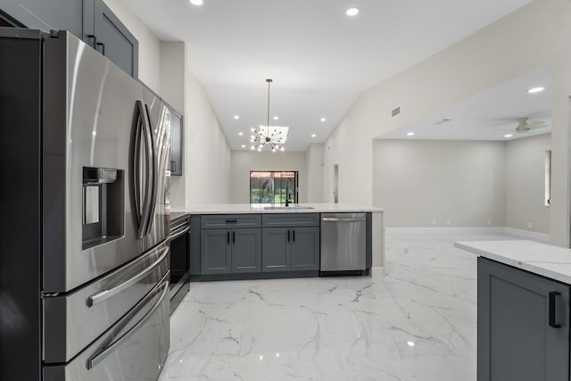 kitchen with pendant lighting, sink, ceiling fan with notable chandelier, gray cabinetry, and stainless steel appliances