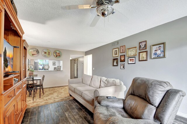 living room featuring a textured ceiling, dark hardwood / wood-style flooring, and ceiling fan