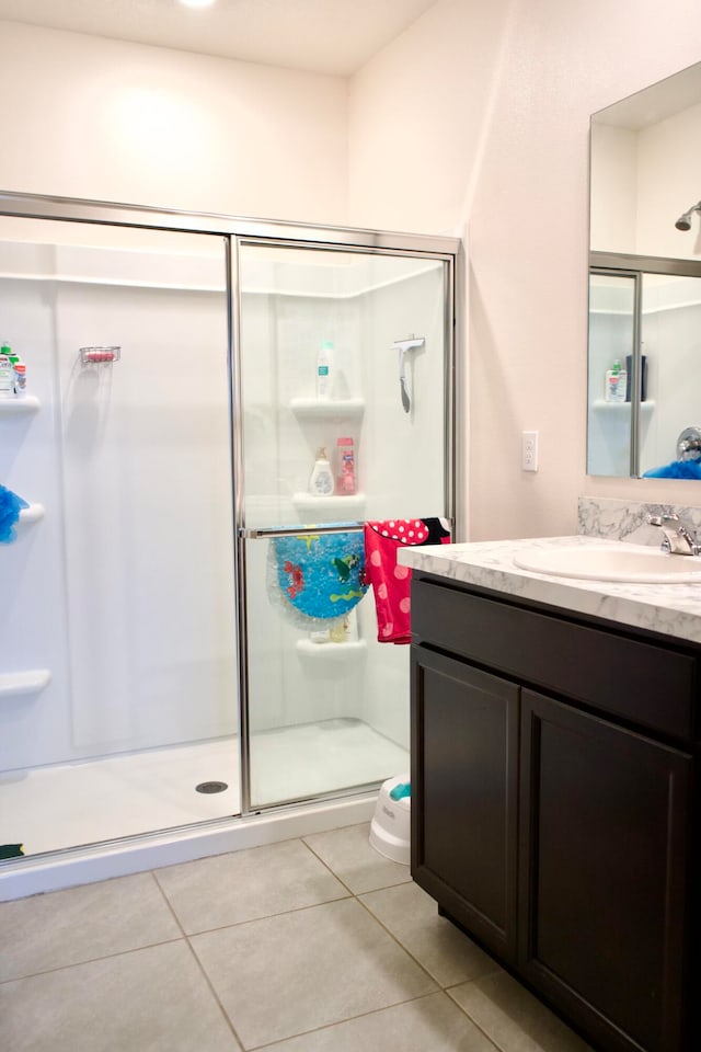 bathroom with tile patterned floors, a shower with shower door, vanity, and toilet