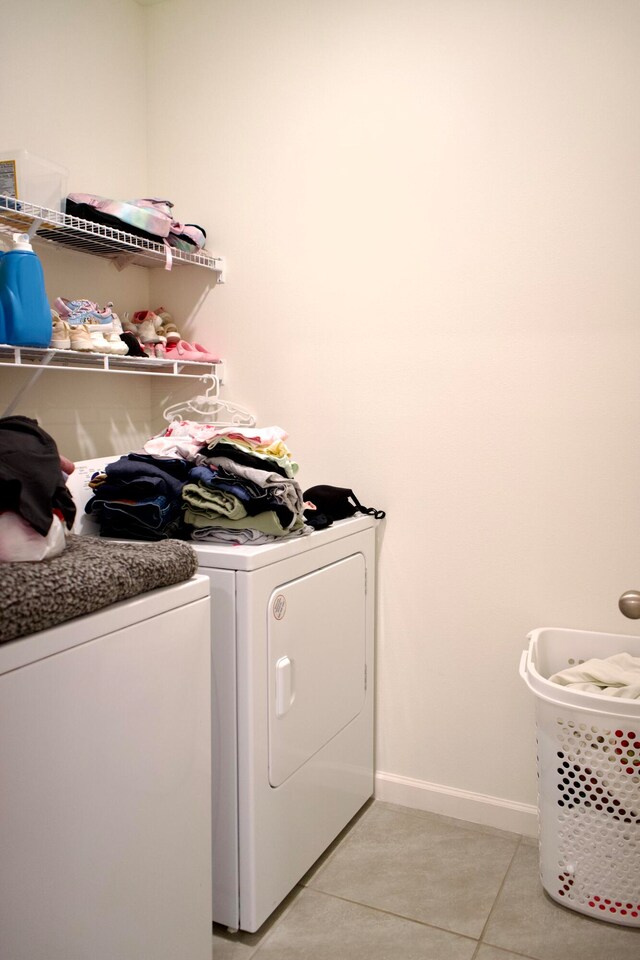 washroom with washer and clothes dryer and light tile patterned floors