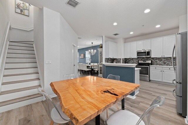 dining area featuring light hardwood / wood-style floors and an inviting chandelier