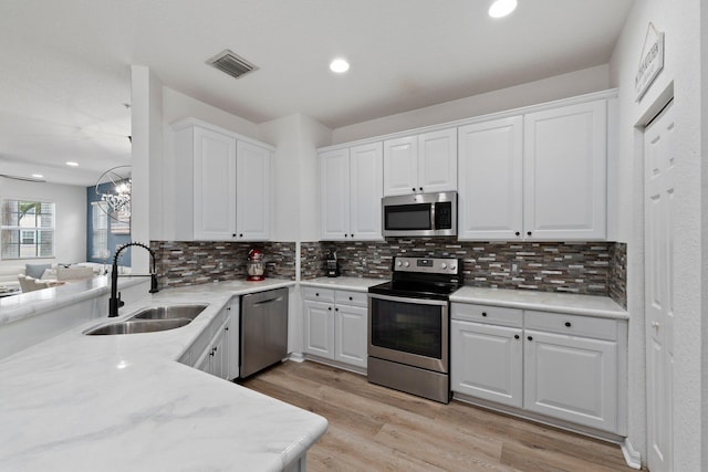 kitchen featuring appliances with stainless steel finishes, sink, white cabinets, and light hardwood / wood-style floors