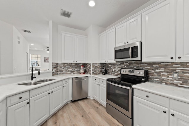 kitchen with white cabinetry, appliances with stainless steel finishes, sink, and light wood-type flooring