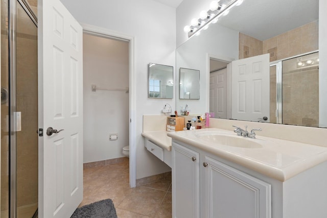 bathroom with vanity, toilet, tile patterned flooring, and a shower with door