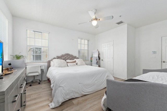 bedroom featuring ceiling fan, light hardwood / wood-style floors, and multiple windows