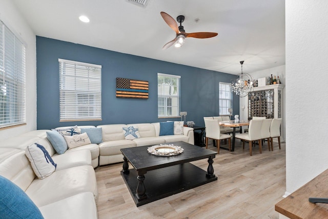 living room with ceiling fan with notable chandelier and light hardwood / wood-style floors