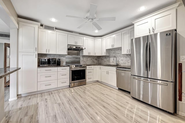 kitchen with white cabinetry, light hardwood / wood-style flooring, backsplash, appliances with stainless steel finishes, and ceiling fan