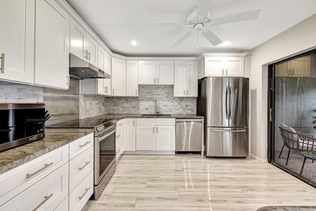 kitchen with white cabinetry, sink, decorative backsplash, dark stone counters, and stainless steel appliances