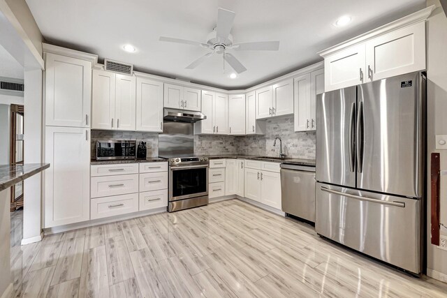 kitchen with appliances with stainless steel finishes, sink, white cabinets, and backsplash