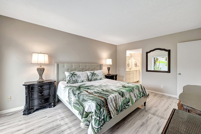 bedroom with connected bathroom and light hardwood / wood-style floors