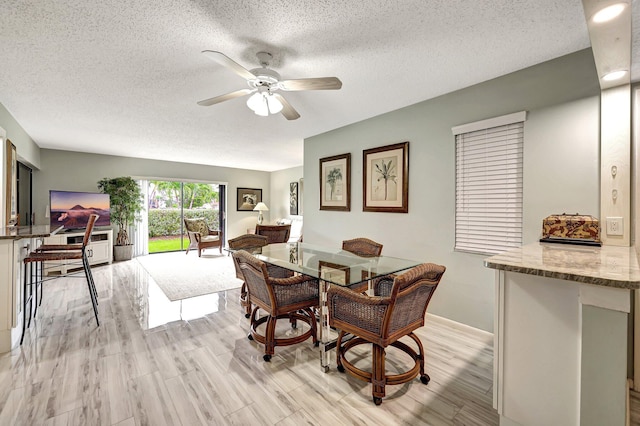 dining area featuring a textured ceiling, ceiling fan, and light wood-type flooring