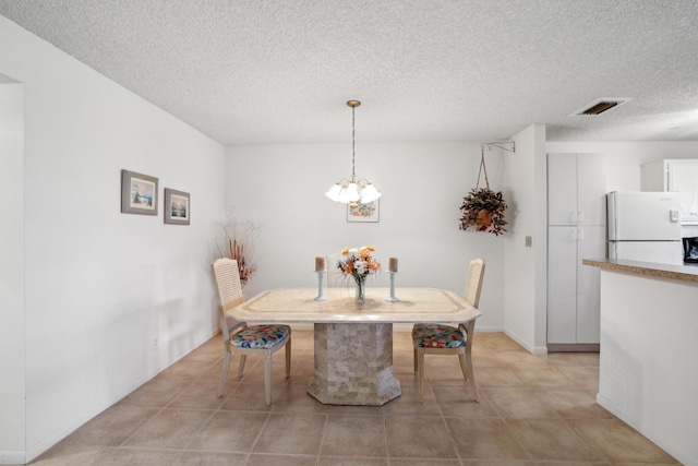 tiled dining area with a textured ceiling and a notable chandelier