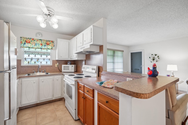 kitchen featuring a wealth of natural light, sink, white cabinets, kitchen peninsula, and white appliances