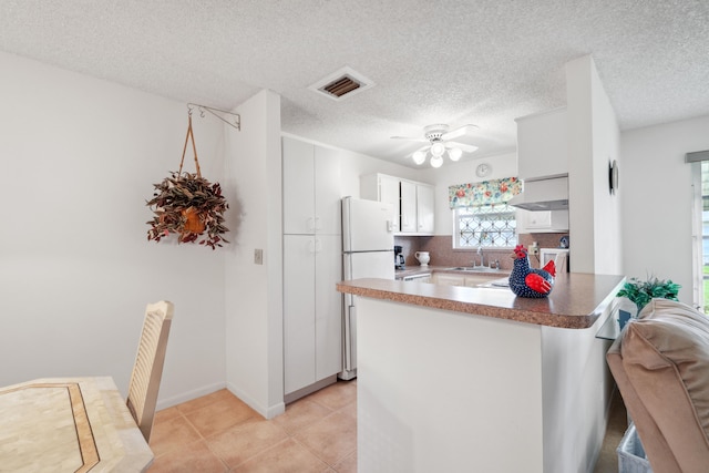 kitchen featuring sink, white cabinets, white fridge, ceiling fan, and wall chimney range hood