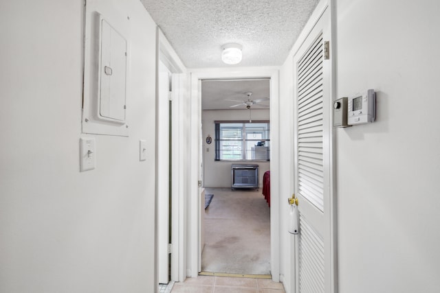 hallway featuring light colored carpet and a textured ceiling