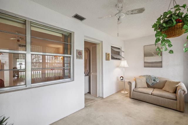 living room featuring light carpet, a textured ceiling, and ceiling fan