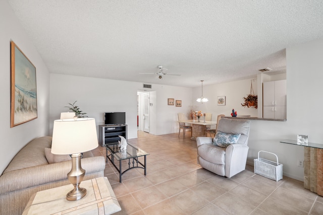 tiled living room with ceiling fan with notable chandelier and a textured ceiling