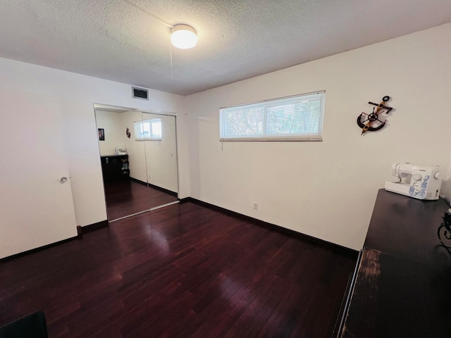 spare room with a textured ceiling and dark hardwood / wood-style floors